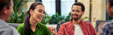 Young cheerful asian business woman discussing project results with colleagues while working together in the modern officeの写真素材