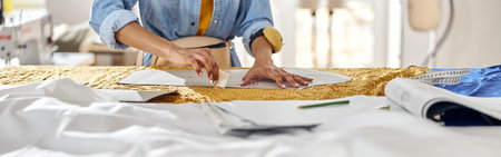 African-American seamstress draws pattern on fabric with tailors chalk at large cutting tableの写真素材