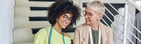 African-American dressmaker shows tablet to mature colleague usiの写真素材