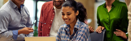 Group of happy multiracial business people looking at laptop screen, discussing project results and smiling while working together in the modern office or coworking spaceの写真素材