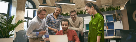 Business professionals at work. Multicultural team, group of young cheerful business people analyzing data, looking at laptop screen while working together in the officeの写真素材