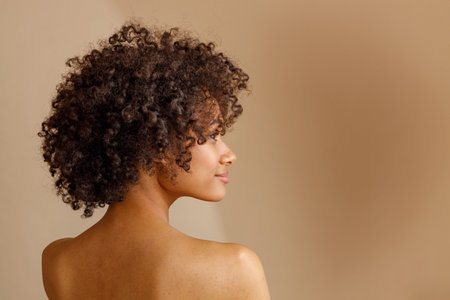 Charming multiracial woman posing against beige wallの写真素材