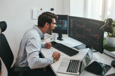 I am a winner Happy young trader in formalwear and eyeglasses shouting and feeling excited while looking at trading charts and financial data in the office.の写真素材