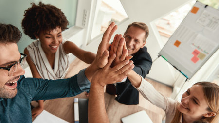Well done Business people giving each other high-five and smiling while working together in the modern officeの写真素材