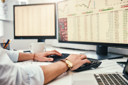 Businessman at work. Cropped photo of male traders hands with watch on his wrist working on computer and analyzing financial data while sitting in his office.の写真素材