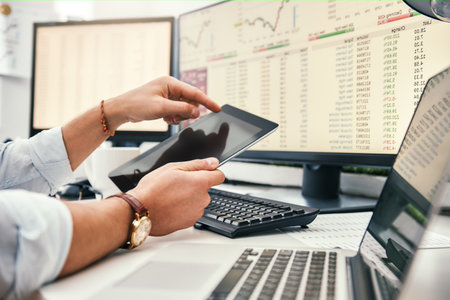 Modern businessman. Cropped photo of young trader in formal wear and watch on his hand using digital tablet and analyzing data while working in his office.の写真素材