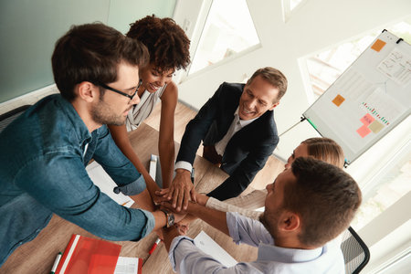 Top view of business people holding hands together while sitting in the modern officeの写真素材