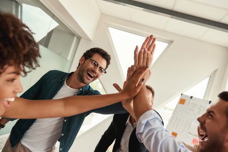 Our success Business people giving each other high-five and smiling while working together in the modern officeの写真素材