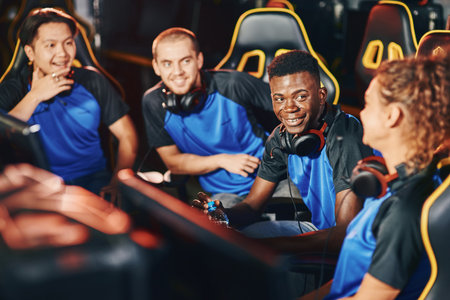 Happy professional multiracial cybersport team talking and discussing game while participating in eSport tournamentの写真素材