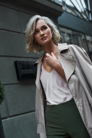 Fashion. Young stylish woman walking on the city street looking aside pensive close-upの写真素材