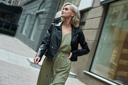 Fashion. Young stylish woman walking on the city street looking aside smiling happyの写真素材