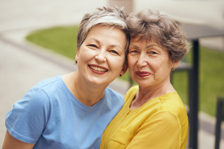 Close up of happy middle age women hug and look at camera on city street. Female friendshipの写真素材