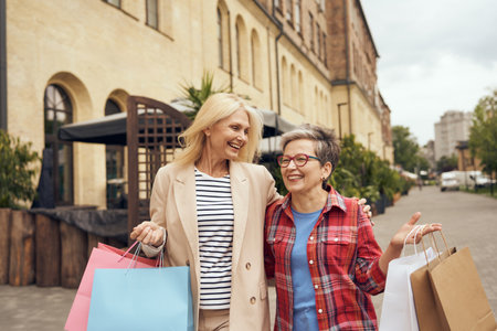 Joyful old women friends after shopping having fun while walking outdoorsの写真素材