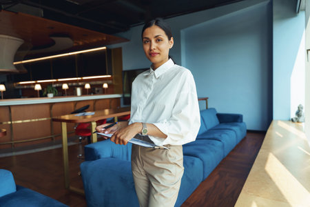Attractive woman analyst with documents standing in coworking and looking at cameraの写真素材