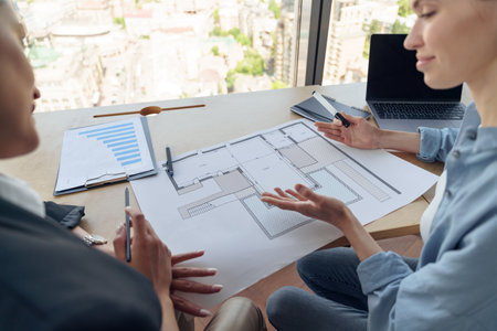 Back view of two design engineer working with project documents sitting in office near window