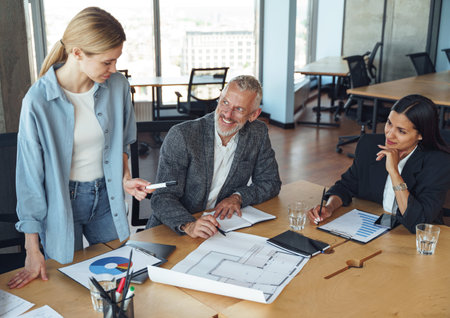 Team of focused professional design engineers working with project documents in modern officeの写真素材