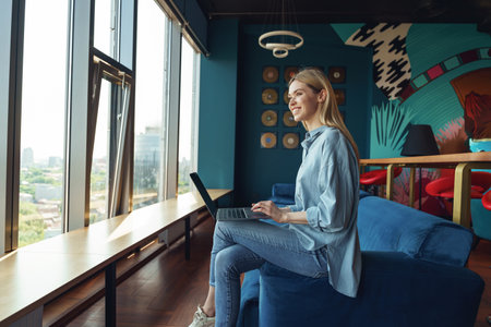 Young business woman in casual clothes working on laptop while sitting in cozy coworkingの写真素材
