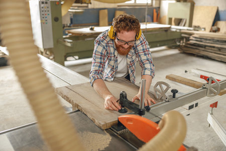 Professional carpenter cutting wooden board at sawmill carpentry manufacturing . Sawing machineの写真素材