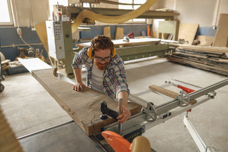 Professional carpenter cutting wooden board at sawmill carpentry manufacturing . Sawing machineの写真素材