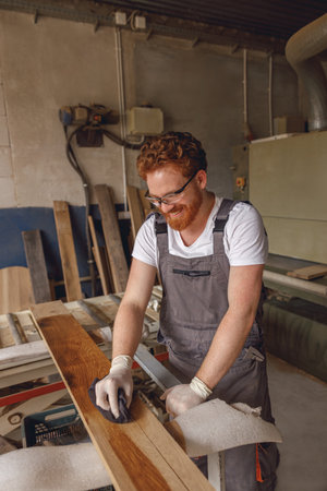 Craftsman coating a wooden board with protective oil in a workshop. Process of making a wood tableの写真素材