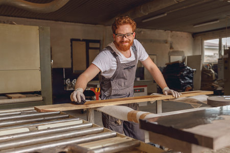 Craftsman coating a wooden board with protective oil in a workshop. Process of making a wood tableの写真素材