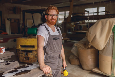 Professional woodworker in eyeglasses standing on the background on carpentry workshopの写真素材