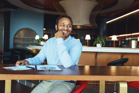 Happy male analyst working with documents while sitting on desk in coworkingの写真素材