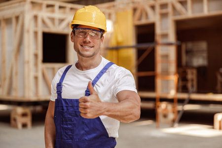 Cheerful male worker in safety helmet giving thumbs up