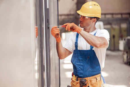 Serious male worker fixing door at construction site