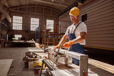 Smiling male carpenter using woodworking machine in workshopの写真素材