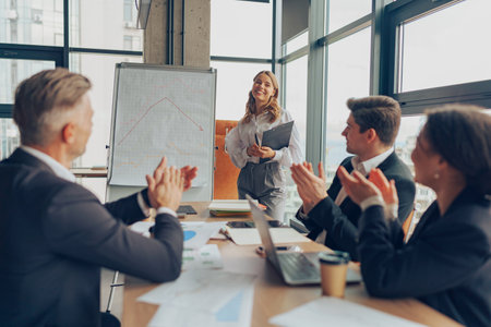 Smiling female entrepreneur discussing her strategy with business team in a modern workspace