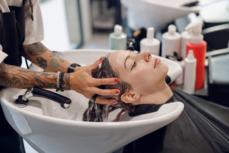 Close up of female barber washes the hair of woman in beauty salonの写真素材