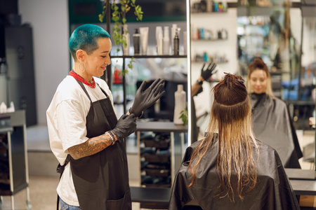 Professional colorist putting on gloves before coloring hair in beauty salonの写真素材