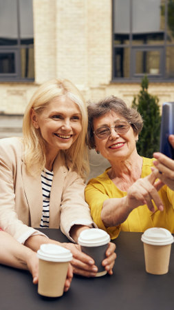 A Joyful Coffee Moment Shared Between Friends Captured in a Beautiful Setting Outdoorsの写真素材
