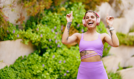 An Energized Woman Joyfully Dancing Outdoors While Wearing Stylish Athletic Wearの写真素材