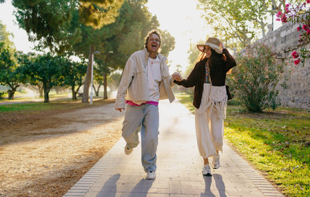 A Joyful Couple Happily Walking Together in Nature While Enjoying the Warm Sunshineの写真素材