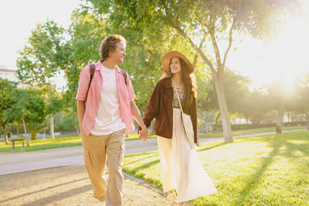 A Couple Enjoying a Joyful Walk Hand in Hand in a Beautiful Sunlit Park on a Lovely Dayの写真素材