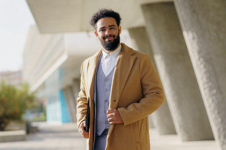 A Stylish Man in a WellFitted Overcoat is Posing Confidently Outdoors Against a City Backdropの写真素材