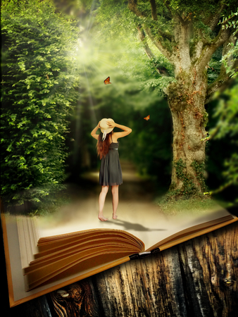 Photo manipulation of young girl standing on open book with magic forestの写真素材