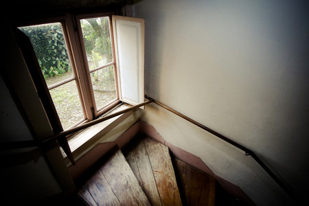Aged window and ladder in old house with low afternoon lightの写真素材