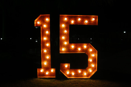 Number fifteen with lights on and clear - fifteen years - fifteen illuminated - large and clear number against dark backgroundの写真素材