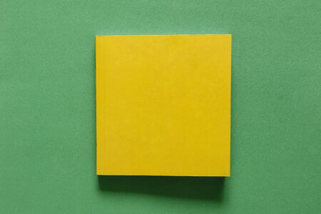 yellow square book on rough green matte table