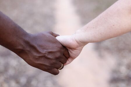 white hand and black hand united - Grooms hands joined using wedding rings - golden wedding rings