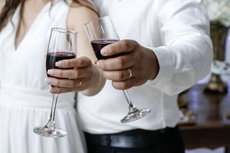 hands detail with wedding rings and wine glasses - grooms toast - golden wedding ringsの写真素材