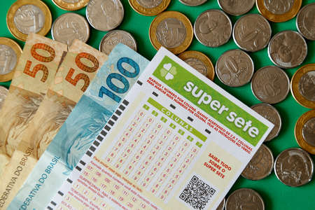 Minas Gerais, Brazil - February 22, 2021: cash notes, coins and lottery ticket Caixa Super Sete