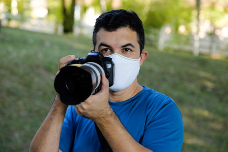 white man wearing photo camera and respiratory mask during workの写真素材