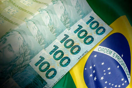Close up of 100 Real Brazilian banknotes in front of the national flag. finance and business conceptの写真素材