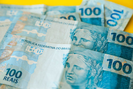money from brazil stacked on yellow surface - several hundred real billsの写真素材