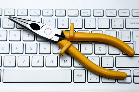 metal pliers tool and yellow insulation and computer keyboard with light toneの写真素材