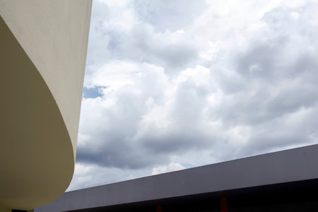 building and architectural detail - curved and straight shapes between cloudsの写真素材